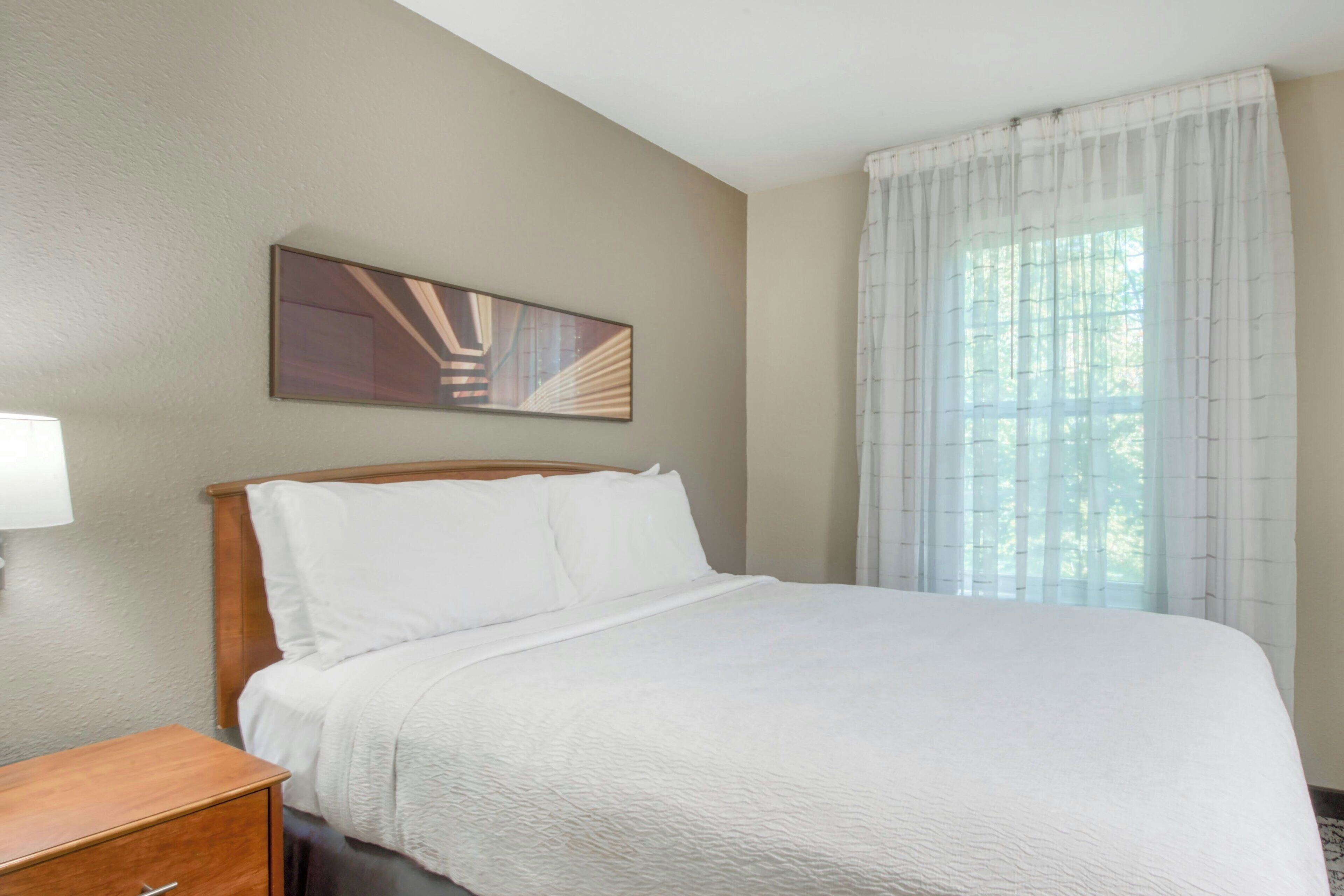 Una cama bien hecha con ropa blanca en una habitación de hotel.