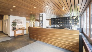 A reception area with a wooden reception desk, a plant, and a shoe display.