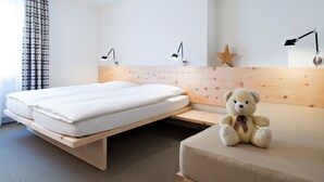 A hotel room with a bed, a small sofa, a teddy bear, and a star decoration on the wall.