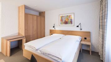 Un dormitorio ordenado con una cama de madera, un escritorio y una mesita de noche.