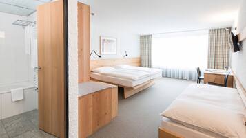 A hotel room with a bed, a desk, a chair, and a shower area.