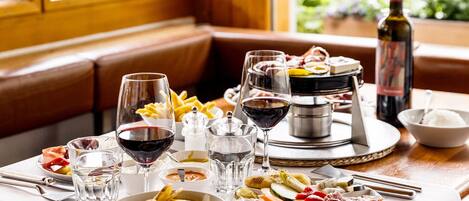 A dining table set with various dishes, glasses of wine, and a bottle of wine.