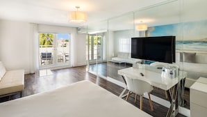 Une chambre d’hôtel moderne dotée d’un grand lit, d’un bureau avec un téléviseur à écran plat, d’une paroi en verre et offrant une vue sur l’extérieur.