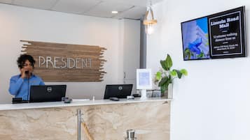 Een receptiebalie met twee computers, een bord met de tekst 'PRESIDENT' en een scherm waarop 'Lincoln Road Mall' staat.