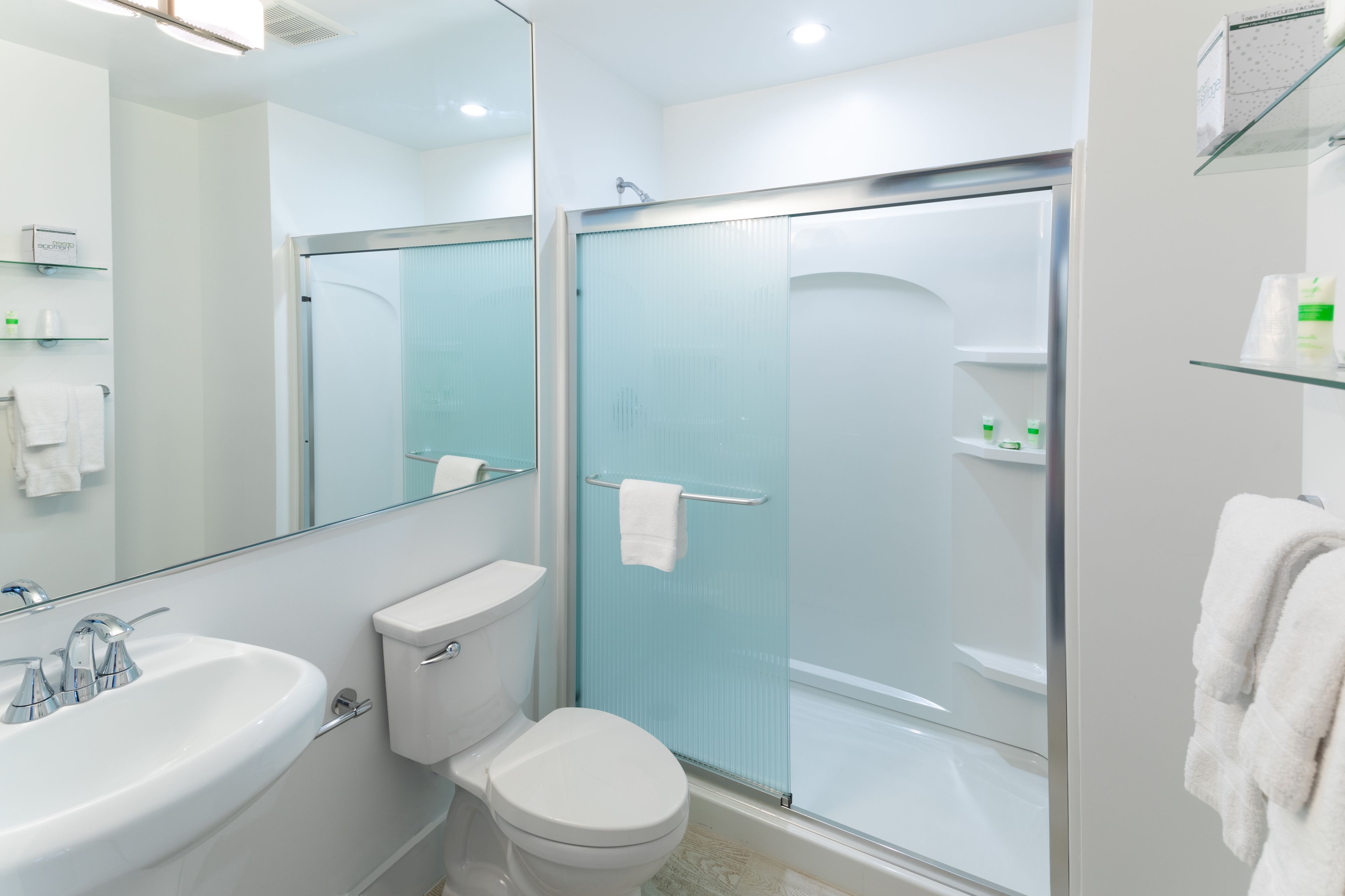 A modern bathroom with a white sink, toilet, and glass-enclosed shower.