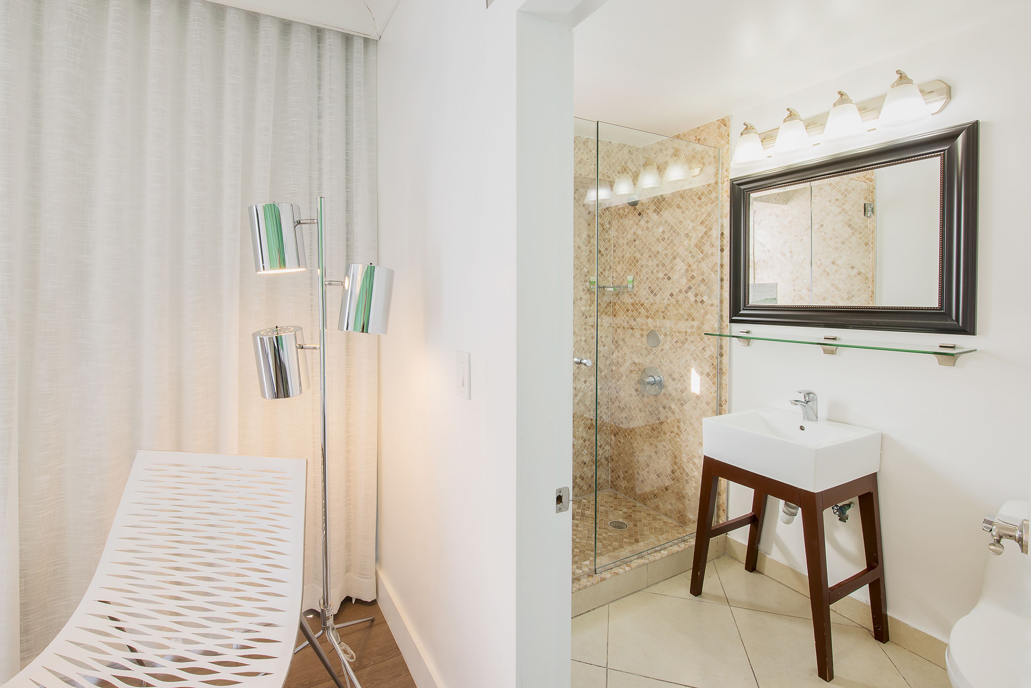 A bathroom with a glass shower enclosure, a white sink, and a large mirror.