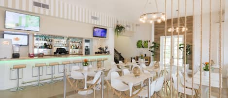 A modern bar area with a counter, bar stools, and a television screen.