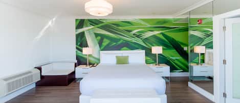 A modern hotel room with a large bed, a bench, a wall-mounted heater, and a green leaf-themed wall mural.
