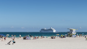 Une plage avec des gens, des parasols et une tour de surveillance des sauveteurs.