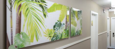 A hallway with a large botanical print on the wall, a white door, and a patterned carpet.