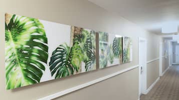 Un pasillo decorado con varias pinturas de hojas tropicales.