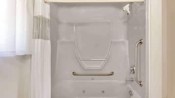 A white bathtub with a shower curtain, grab bars, and a handheld showerhead.