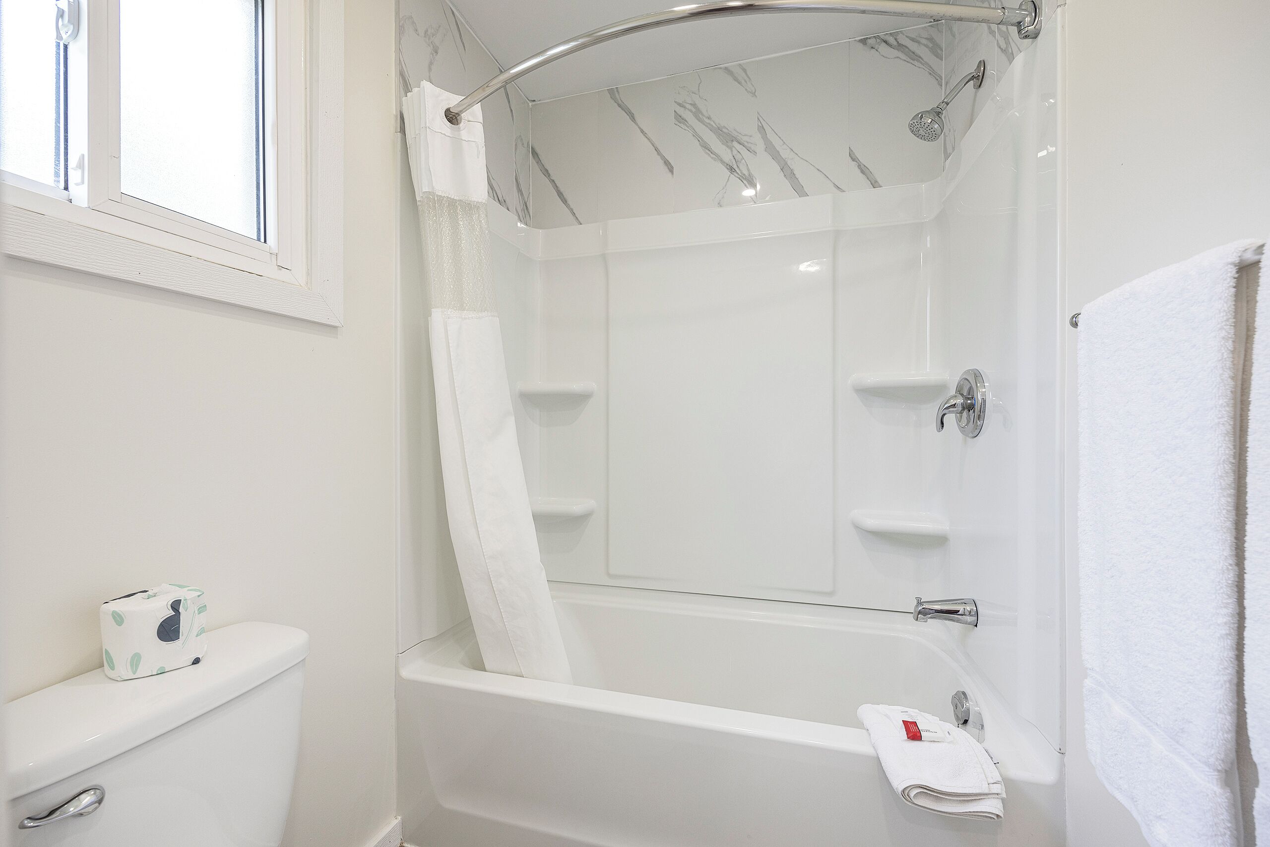 Un baño con una bañera blanca, ducha e inodoro.