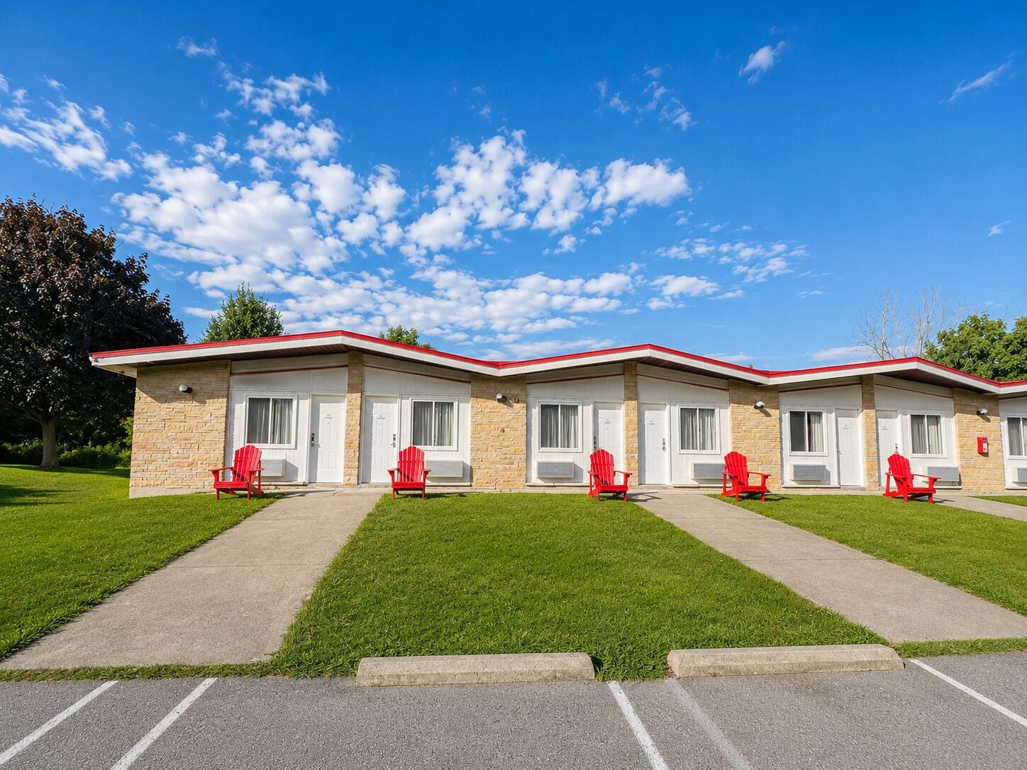 A motel with four rooms, each with a red chair outside.