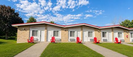 A motel with four rooms, each with a red chair outside.