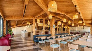 A spacious restaurant with wooden beams, striped flooring, and multiple seating areas including booths and tables. - Ramada by Wyndham 1000 Islands/Gananoque (Gananoque)