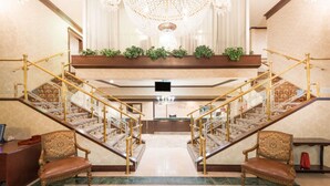 A grand lobby with a central staircase, a chandelier, and a reception desk. - Ramada by Wyndham St. John's (St. John's)