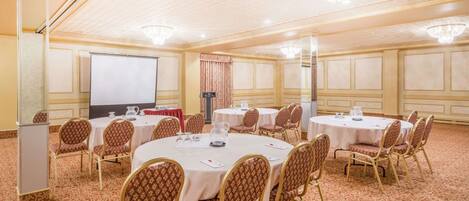 A conference room with round tables, chairs, and a projector screen.