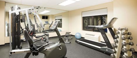 A gym with cardio machines, weightlifting equipment, and exercise balls.