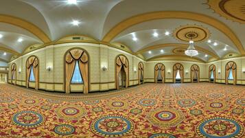 Un vaste hall doté d’un tapis à motifs, de plafonds en arc de cercle et d’un lustre.