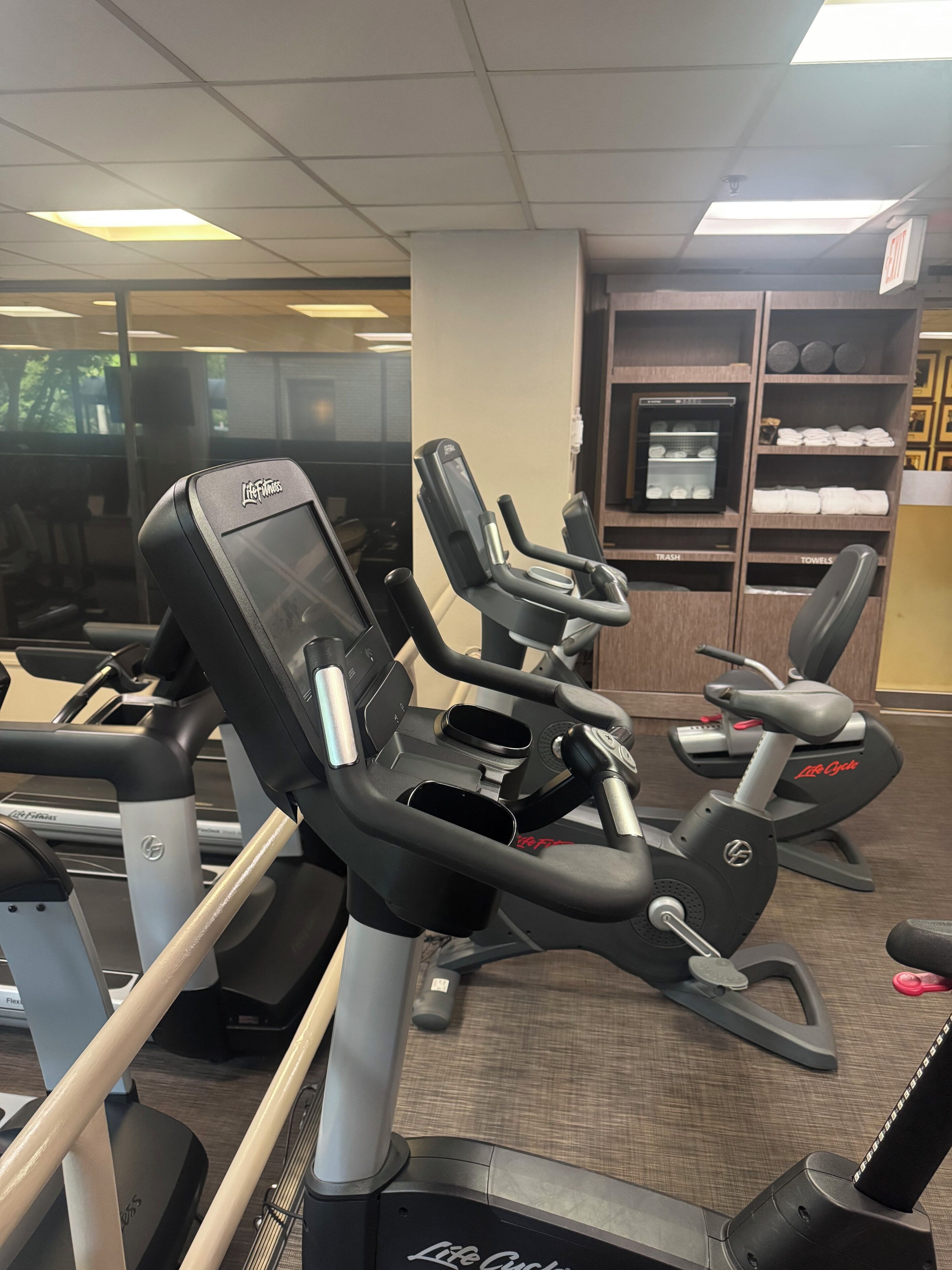 Un gimnasio con cintas de correr, máquinas de pesas y una televisión instalada en la pared.