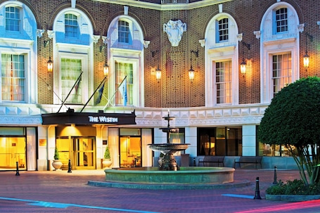 A hotel facade with arched windows, a fountain, and a sign for "The Westin."