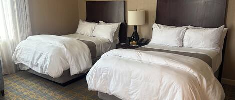 A hotel room with two beds, a nightstand with a lamp, and a patterned carpet.