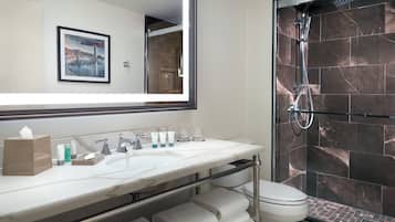 Une salle de bain moderne avec un grand miroir, un lavabo en marbre et une douche à parois de verre.