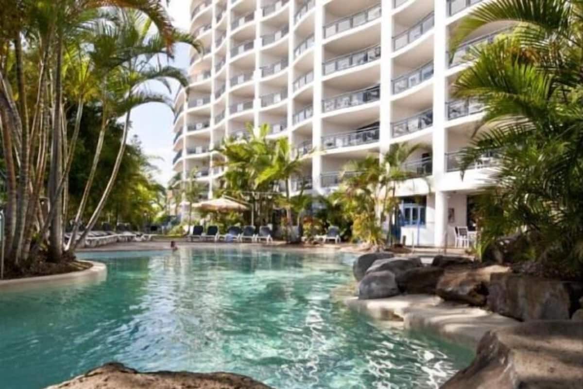 Un hôtel doté d’une piscine, de palmiers et d’un immeuble à plusieurs étages.