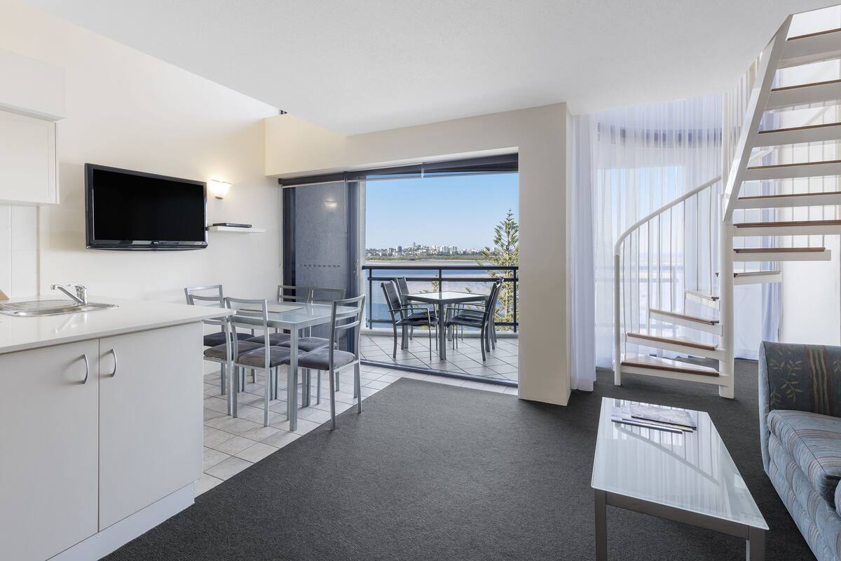 Un appartement moderne comprenant une cuisine, un coin repas et un salon avec un canapé et un escalier.