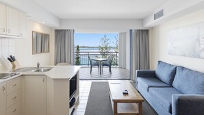 Eine moderne Küche mit Essbereich, einer Couch und einem Balkon mit Meerblick.