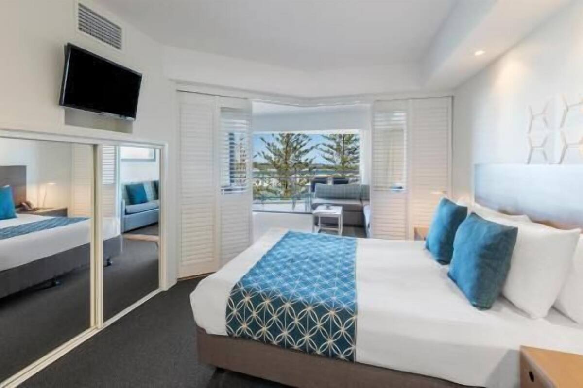 Une chambre d’hôtel avec un lit, une télévision, un balcon avec vue et un bureau.