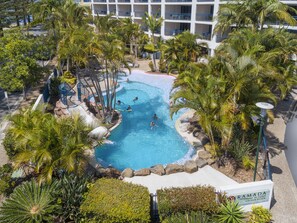 A resort pool surrounded by palm trees and a sign for Ramada Resort. - Ramada Resort by Wyndham Golden Beach (Golden Beach)