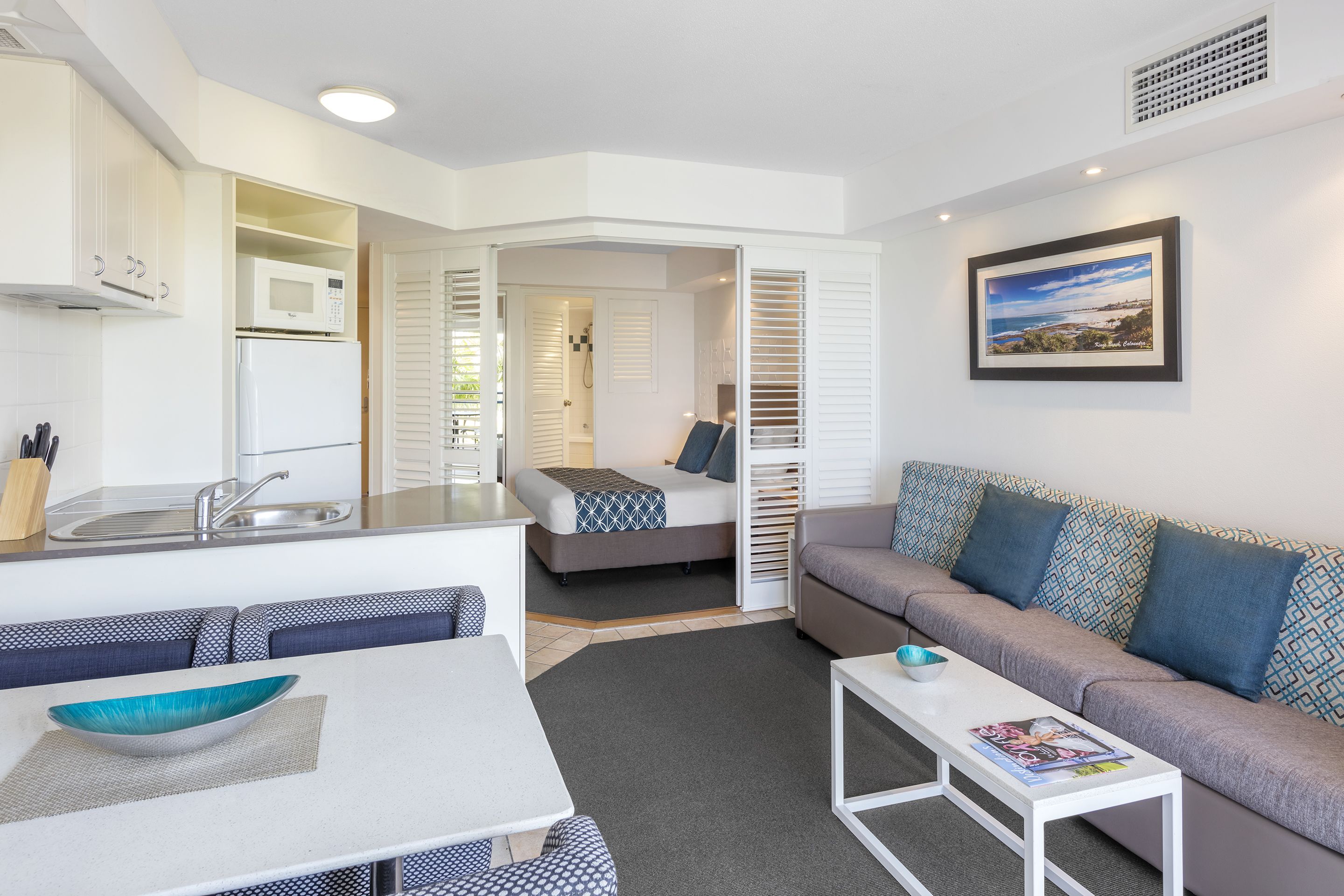 Un espacio habitable compacto con kitchenette, un sofá, una mesa de comedor y una cama.