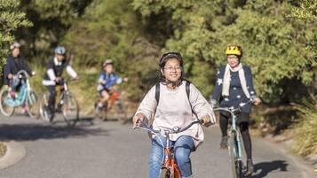 Un grupo de ciclistas en un sendero pavimentado rodeado de árboles.