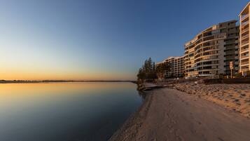 A beachfront hotel with multiple balconies, a sandy beach, and a calm sea.