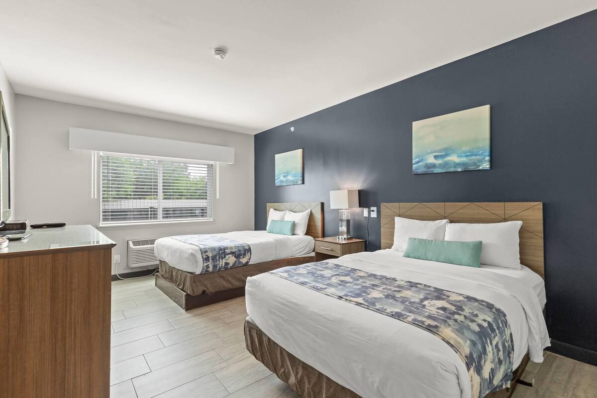 Een hotelkamer met twee bedden, een bureau en kunstwerken aan de wanden.