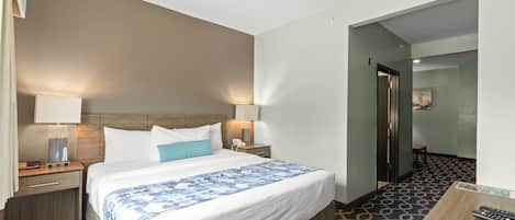 Habitación de hotel con una cama grande, mesitas de noche con lámparas, un escritorio con silla y un suelo estampado.