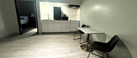Una cocina compacta con comedor, un lavamanos y un refrigerador pequeño.