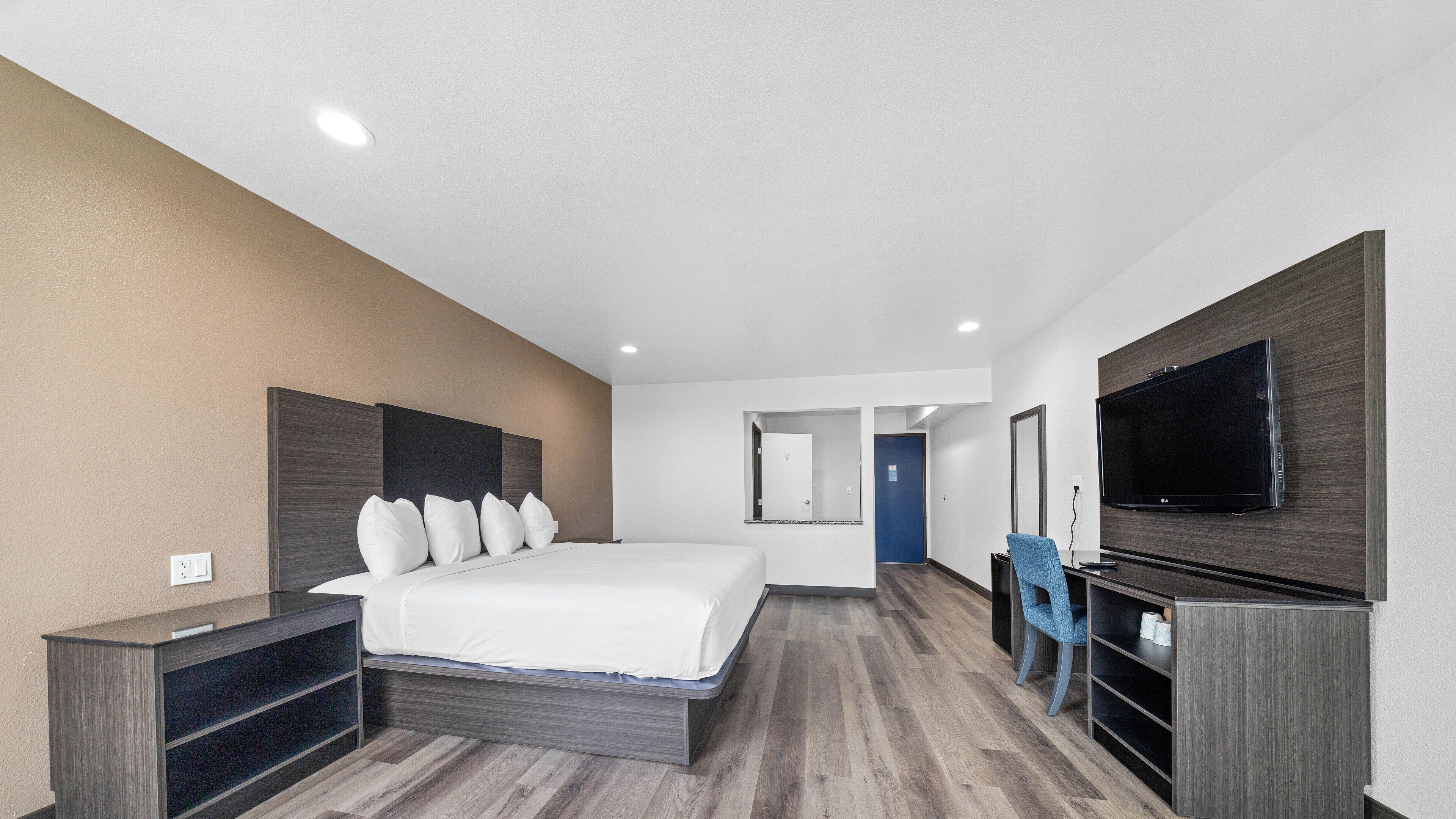 A modern hotel room with a large bed, a TV, a desk, and a wardrobe.