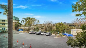 A parking lot with several cars, orange traffic cones, and a building with a green roof in the background. - Motel 6 Oceanside, CA Marina / Camp Pendleton (Oceanside)