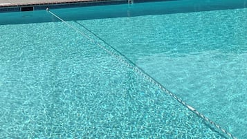 Una piscina al aire libre, sillones reclinables de piscina