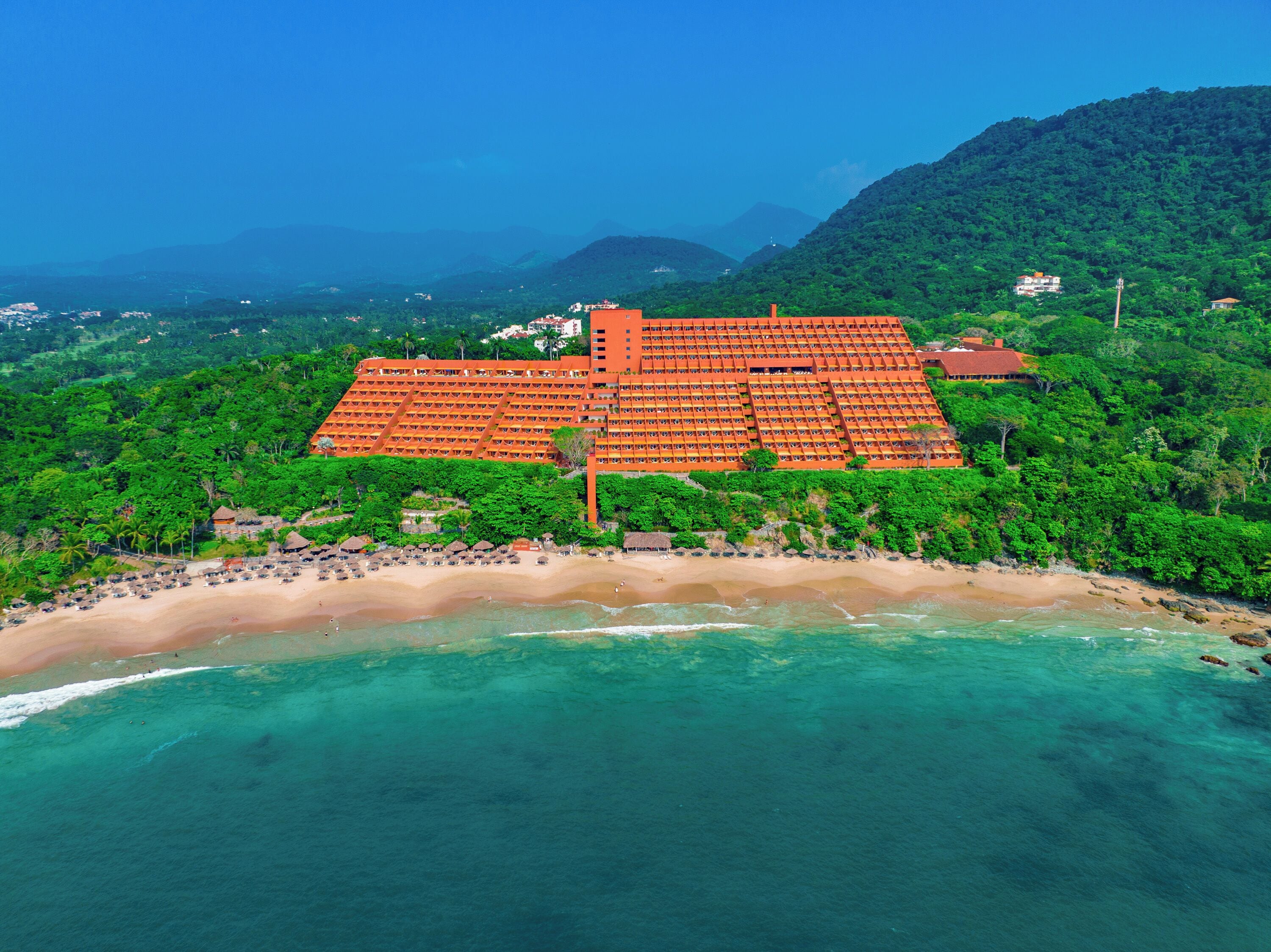 Un grand complexe hôtelier doté d’une plage et bordé par des montagnes.