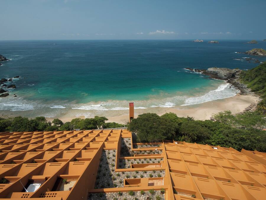 Un hotel frente al mar con tejado escalonado y vistas a la playa y al océano.