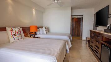 A hotel room with two beds, a ceiling fan, a TV, and a minibar.