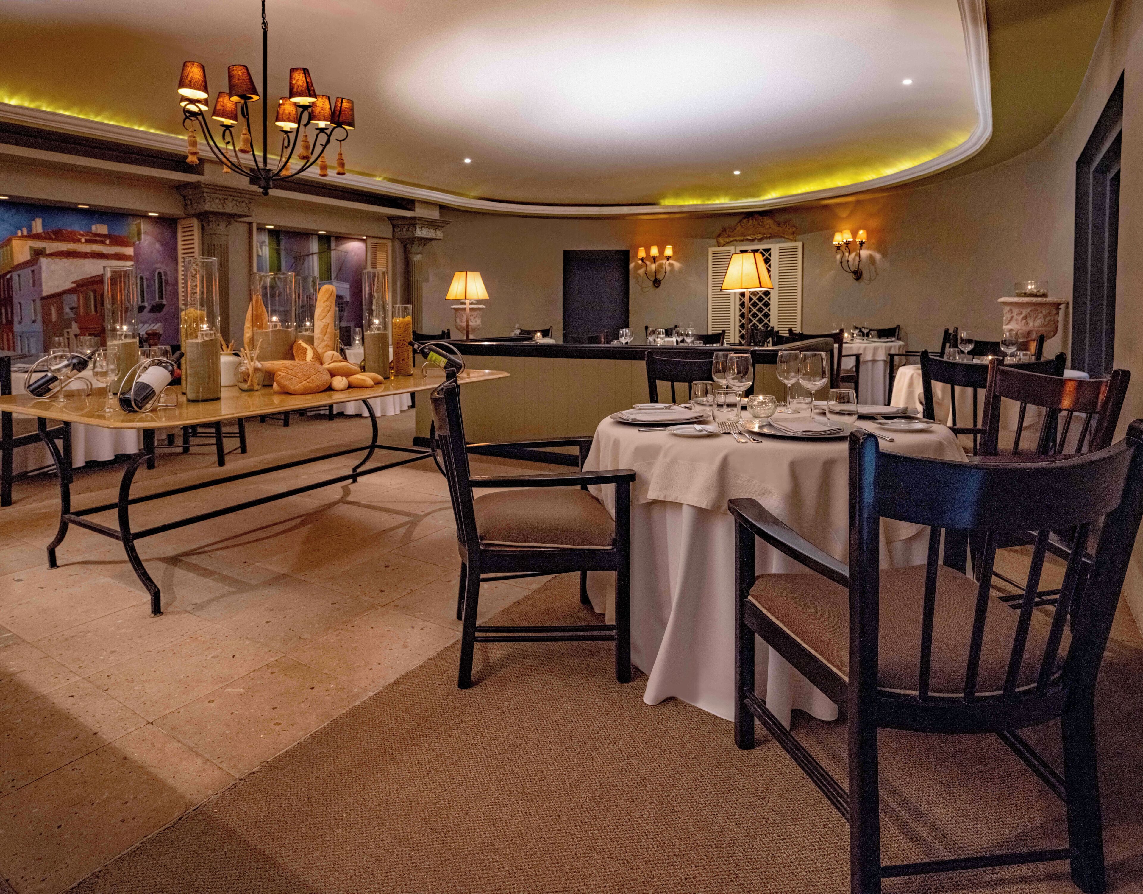 Une salle à manger bien éclairée, avec des tables rondes, des chaises et un lustre.