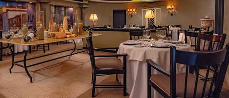 A well-lit dining area with round tables, chairs, and a chandelier.