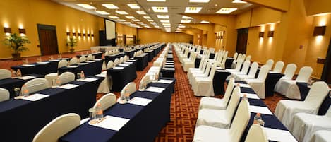 A conference room with rows of tables and chairs, equipped with nameplates and water bottles.