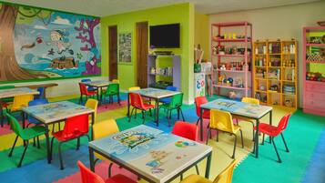 Children can play and learn in this vibrant playroom with tables, chairs, colorful mats, and a large mural.