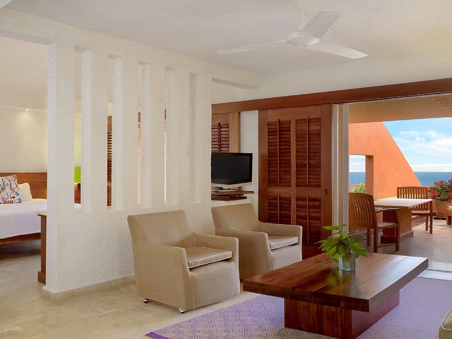 Une chambre d’hôtel avec un lit, une télévision, une table basse et un balcon donnant sur l’océan.